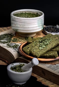 Enjoy with A Cup of Hot Hemp Tea (CBD herbal tea) is served with the Homemade Cannabis Snack Stick, which are on the Old Song Book with dark backgroud. Space for text.