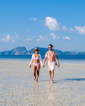 a couple of men and women walking at the beach of Koh Kradan island in Thailand during vacation on a sunny day