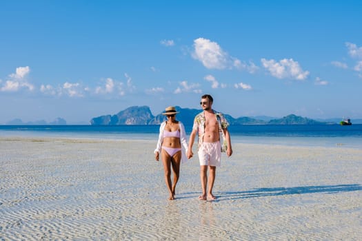 a couple of men and women walking at the beach of Koh Kradan island in Thailand during vacation on a sunny day