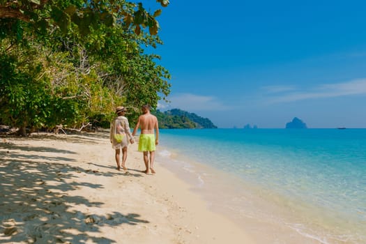 a couple of men and women walking at the beach of Koh Kradan island in Thailand during vacation on a sunny day