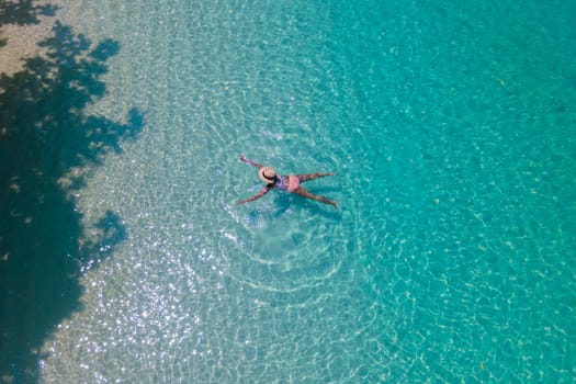 drone view of a Asian woman swimming in the blue turqouse colored ocean of Koh Kradan island in Thailand