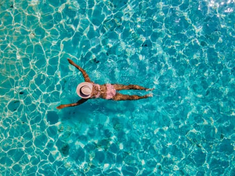 drone view of a Asian woman swimming in the blue turqouse colored ocean of Koh Kradan island in Thailand