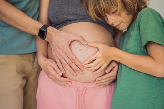 Pregnant Woman, father and first kid child holding hands in a heart shape on her baby bump. Pregnant Belly with fingers Heart symbol.