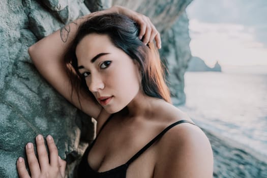 Portrait of cheerful female climber ascending a rock. The athlete girl trains in nature. Woman overcomes difficult climbing route.