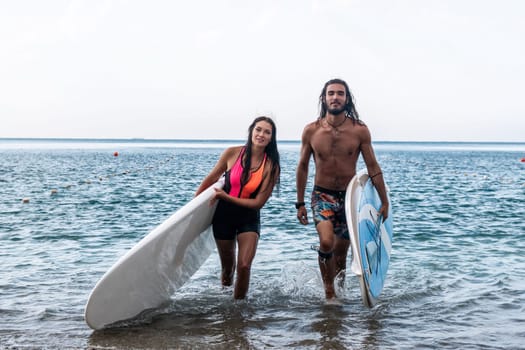 Sea woman and man on sup. Silhouette of happy young woman and man, surfing on SUP board, confident paddling through water surface. Idyllic sunset. Active lifestyle at sea or river