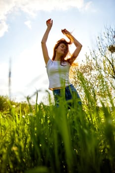 happy woman dancing in high grass field, bottom view. High quality photo