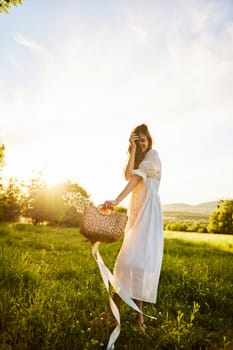 a woman in a long, light dress stands in a chamomile field at sunset and closes herself from the camera with her hands. High quality photo