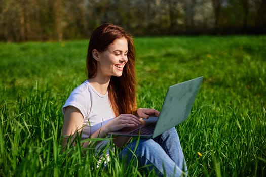 woman in nature working on a laptop on a sunny day. High quality photo