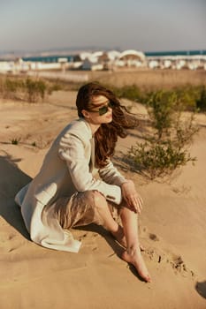 portrait of a beautiful stylish woman relaxing sitting on the sand near the sea. High quality photo