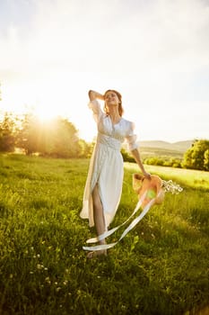 a beautiful woman in a light, summer dress stands in a chamomile field with a basket of flowers in her hands. High quality photo