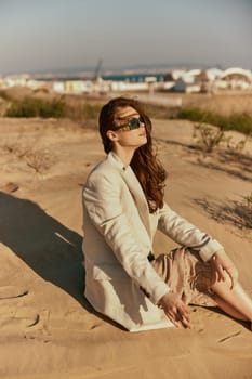 portrait of a beautiful stylish woman relaxing sitting on the sand near the sea. High quality photo