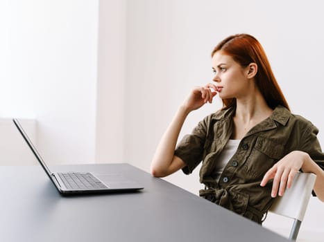 serious, pensive woman working in a bright office behind a laptop. High quality photo
