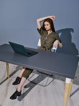 a puzzled woman sits at a laptop with her hand raised to her head. High quality photo