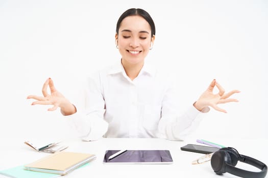 Worplace and working environment. Young woman sits in office with tablet and documents, keeps calm, meditates and smiles, relaxes, white background.