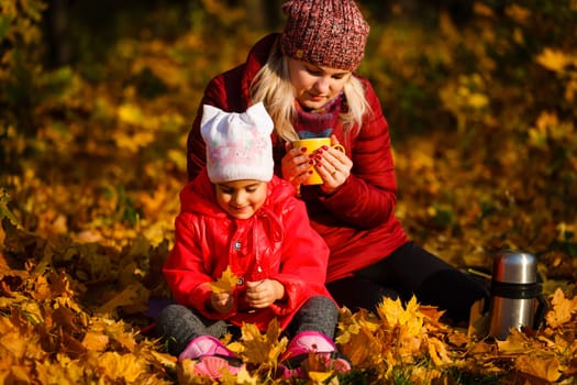 Hello autumn. smiling young mother and daughter in hats outdoors in the city park in autumn having fun time