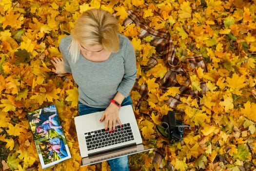 woman with laptop and photo book in autumn park.