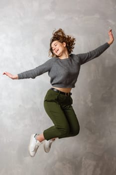 Portrait of cheerful positive girl jumping in the air with raised fists looking at camera isolated.