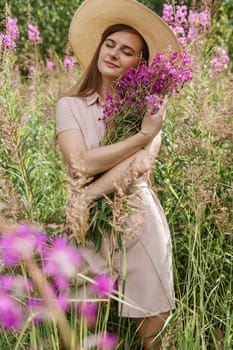 A young woman in nature with a bouquet of pink wild flowers. A bouquet of Ivan-tea in the hands of a woman.