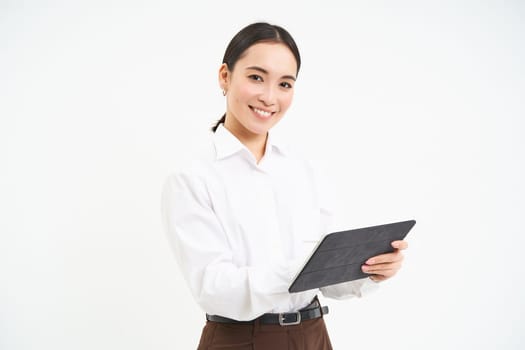 Asian woman professional, standing with digital tablet, working on project, writing down notes for business meeting, standing isolated over white background.