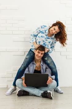 Couple Use Laptop Computer, while Sitting on the Living Floor room of their Apartment. Boyfriend and Girlfriend Talk, Shop on Internet, Choose Product to Order Online, Watch Streaming Service