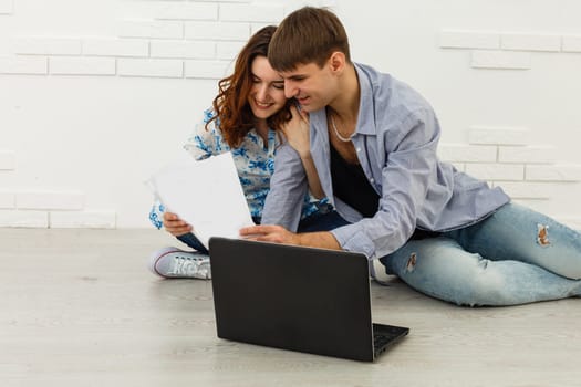 Portrait of happy young couple using laptop on gray background.