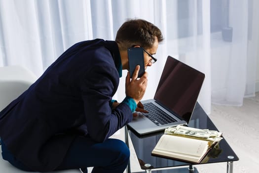 Young business man working at home with laptop and papers on desk