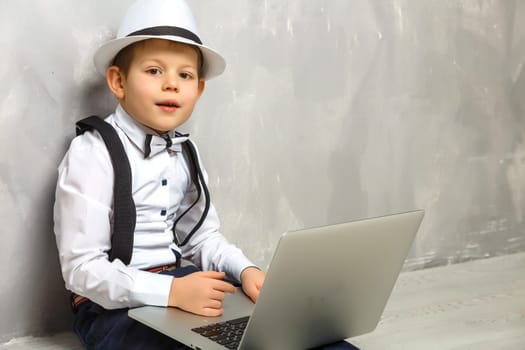 Portrait of Genius. Young boy working on the computer sitting On the floor. Studying. Online learning remotely. Distant school. Distance education. Online courses and knowledge.