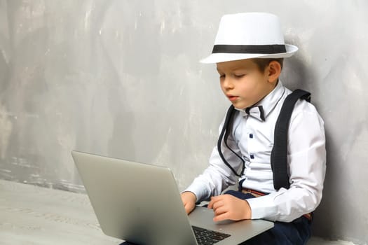 Portrait of Genius. Young boy working on the computer sitting On the floor. Studying. Online learning remotely. Distant school. Distance education. Online courses and knowledge.