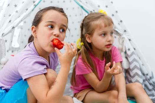 two little girls eating strawberries.