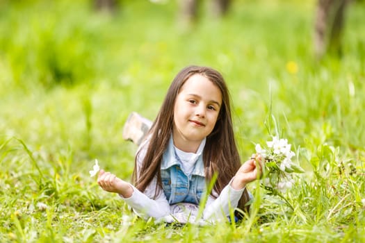 Portrait of a smiling little girl lying on green grass.