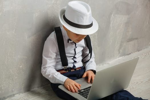 Young man sits on the laminate floor with black laptop. Top view