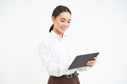 Asian woman professional, standing with digital tablet, working on project, writing down notes for business meeting, standing isolated over white background.