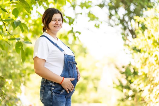 Beautiful pregnant woman relaxing outside in the park