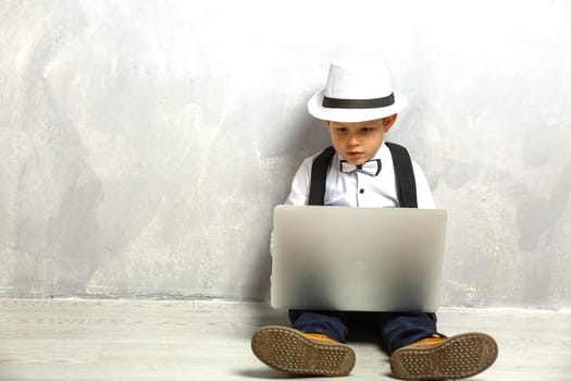 Portrait of Genius. Young boy working on the computer sitting On the floor. Studying. Online learning remotely. Distant school. Distance education. Online courses and knowledge.