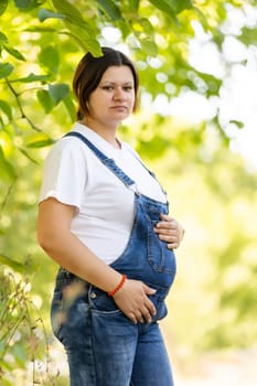 Beautiful pregnant woman relaxing outside in the park