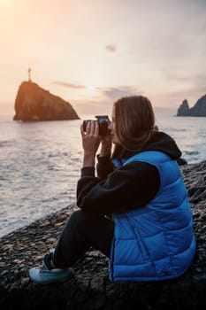 Woman travel sea. Happy tourist taking picture outdoors for memories. Woman traveler looks at the edge of the cliff on the sea bay of mountains, sharing travel adventure journey.