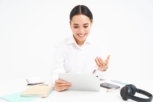 Image of saleswoman, asian businesswoman video chats, has online meeting on digital tablet, sits in her office, isolated on white background.