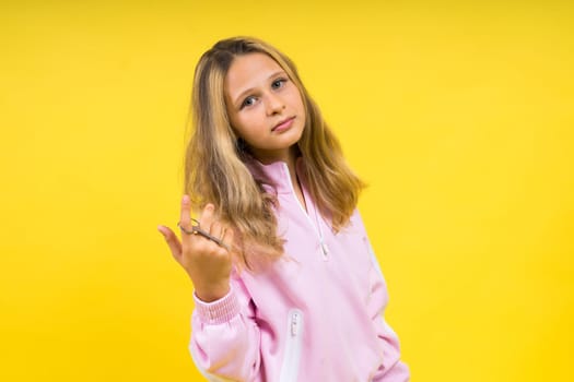 Child adorable girl hairdresser cutting long blonde hair with metallic scissors on a yellow