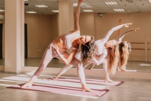 Young woman with long hair in white swimsuit and boho style braclets practicing outdoors on yoga mat by the sea on a sunset. Women's yoga fitness routine. Healthy lifestyle, harmony and meditation