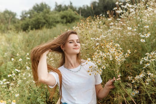 Beautiful young woman in nature with a bouquet of daisies. Field daisies, field of flowers. Summer tender photo.