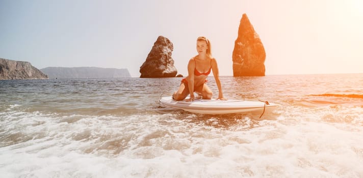 Close up shot of beautiful young caucasian woman with black hair and freckles looking at camera and smiling. Cute woman portrait in a pink bikini posing on a volcanic rock high above the sea