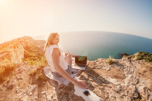 Woman sea laptop. Business woman in yellow hat working on laptop by sea. Close up on hands of pretty lady typing on computer outdoors summer day. Freelance, digital nomad, travel and holidays concept.