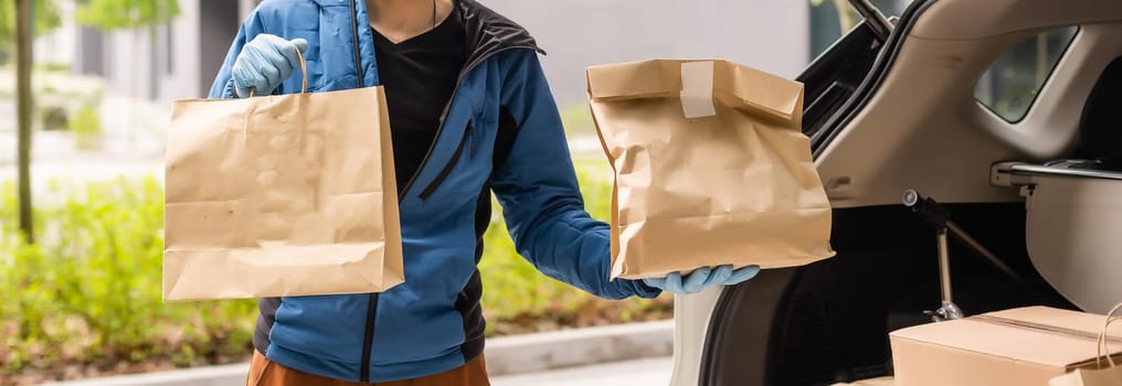 Postal delivery courier man wearing protective face mask in front of cargo van delivering package holding box due to Coronavirus disease or COVID-19.