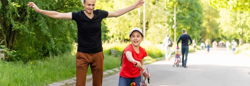 happy father rejoices that her daughter learned to ride a bike.