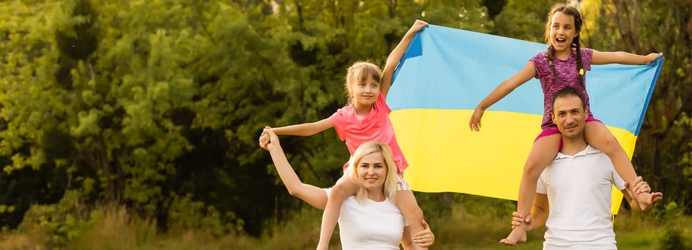 Flag Ukraine in hands of little girl in field. Child carries fluttering blue and yellow flag of Ukraine against background field