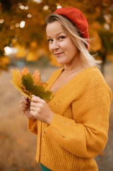 Woman holding autumn leafs in the nature. Autumn woman on leafs background.