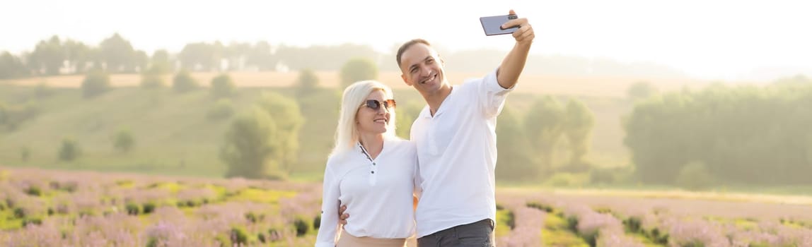 Smiling young couple embracing at the lavender field, holding hands, walking