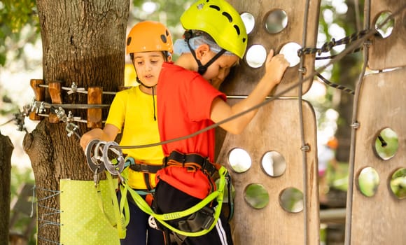 Happy child climbing in the trees. Rope park. Climber child. Early childhood development. Roping park. Balance beam and rope bridges. Rope park - climbing center.