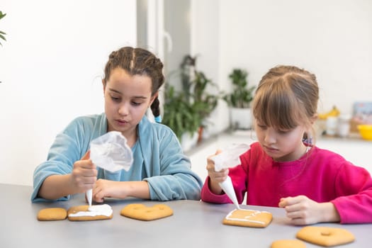 two beautiful sisters decorate and eat delicious cakes at a wooden table.