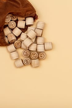 Wooden lotto barrels with brown bag on beige background. Board game lotto. Top view with copy space.